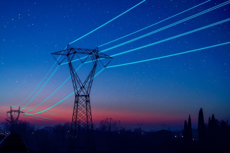 Utility pole with glowing cables over sunset sky
