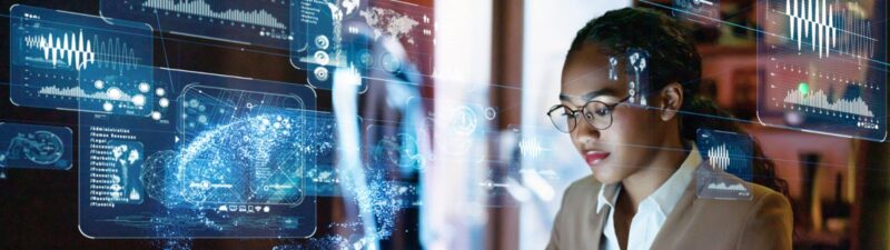 Photo of a woman working at a laptop with technology symbols floating around her