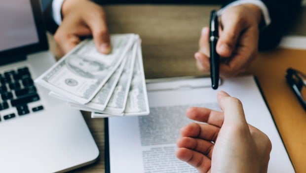 People signing paperwork and exchanging cash