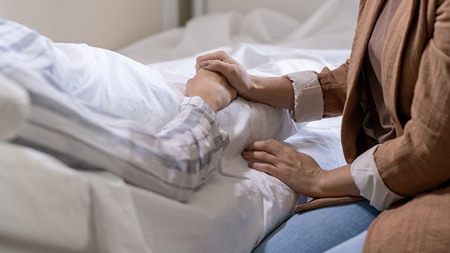 Two people clasping hands in hospital