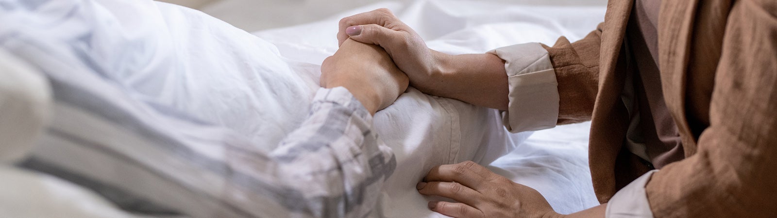 Two people clasping hands in hospital