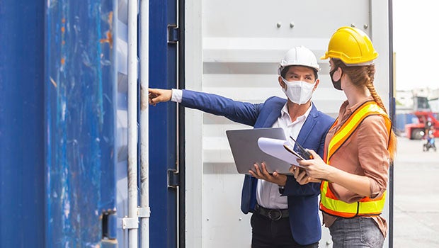 Two construction workers wearing hard hats and face masks
