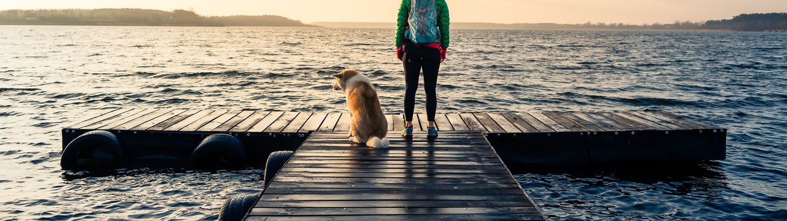 Woman with dog enjoy sunrise at lake